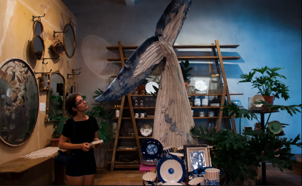 A friend looks at a large paper mache whale tail
