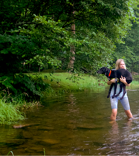 A girl carries her dog upstream