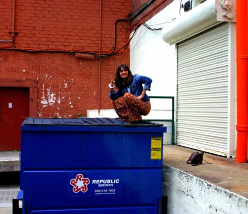 a girl squats on a trash can